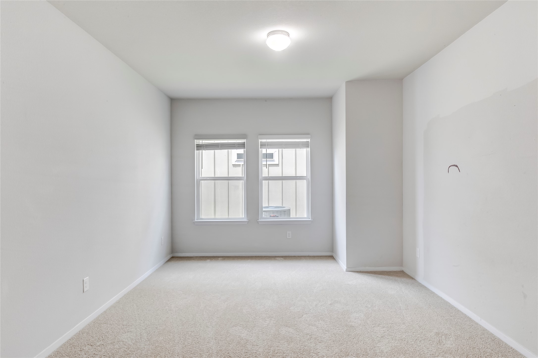 2721 Winding Creek Road Kyle, TX 78640 - Photo 17 of 27 Carpeted room featuring two double-hung windows with blinds, a ceiling-mounted light fixture, and neutral-toned walls