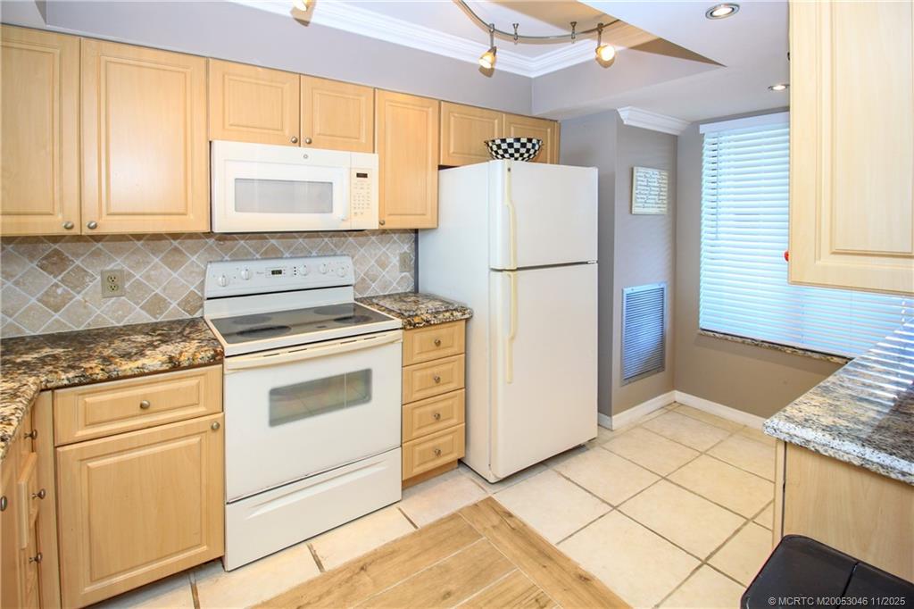 4720 Northeast Sandpebble Trace, Unit 403 Stuart, FL 34996 - Photo 11 of 40 a kitchen with white cabinets and white appliances