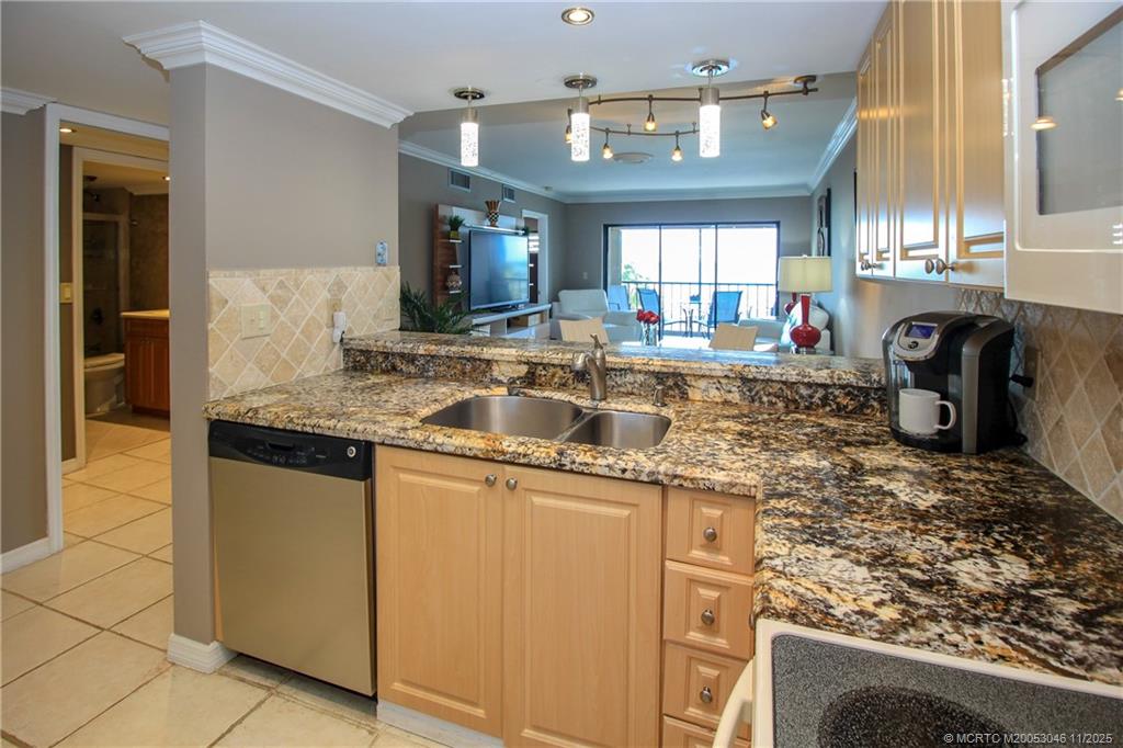 4720 Northeast Sandpebble Trace, Unit 403 Stuart, FL 34996 - Photo 13 of 40 a kitchen with kitchen island granite countertop a sink stove and cabinets