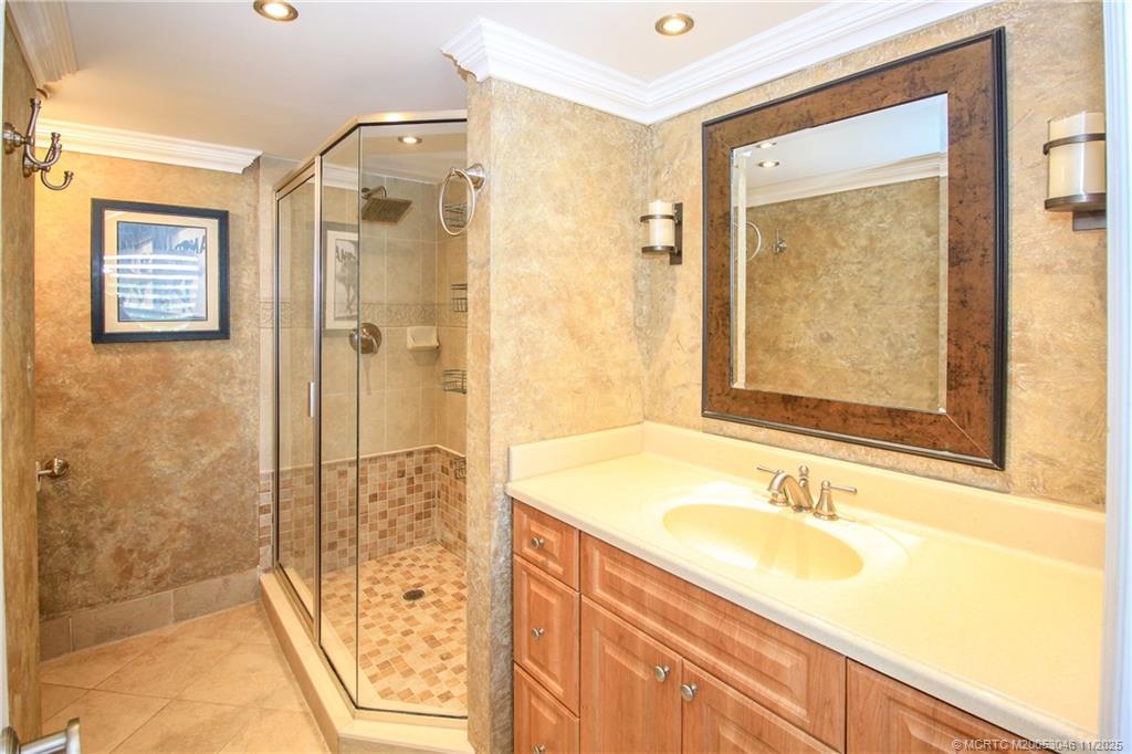 4720 Northeast Sandpebble Trace, Unit 403 Stuart, FL 34996 - Photo 16 of 40 a bathroom with a granite countertop sink a shower and a mirror