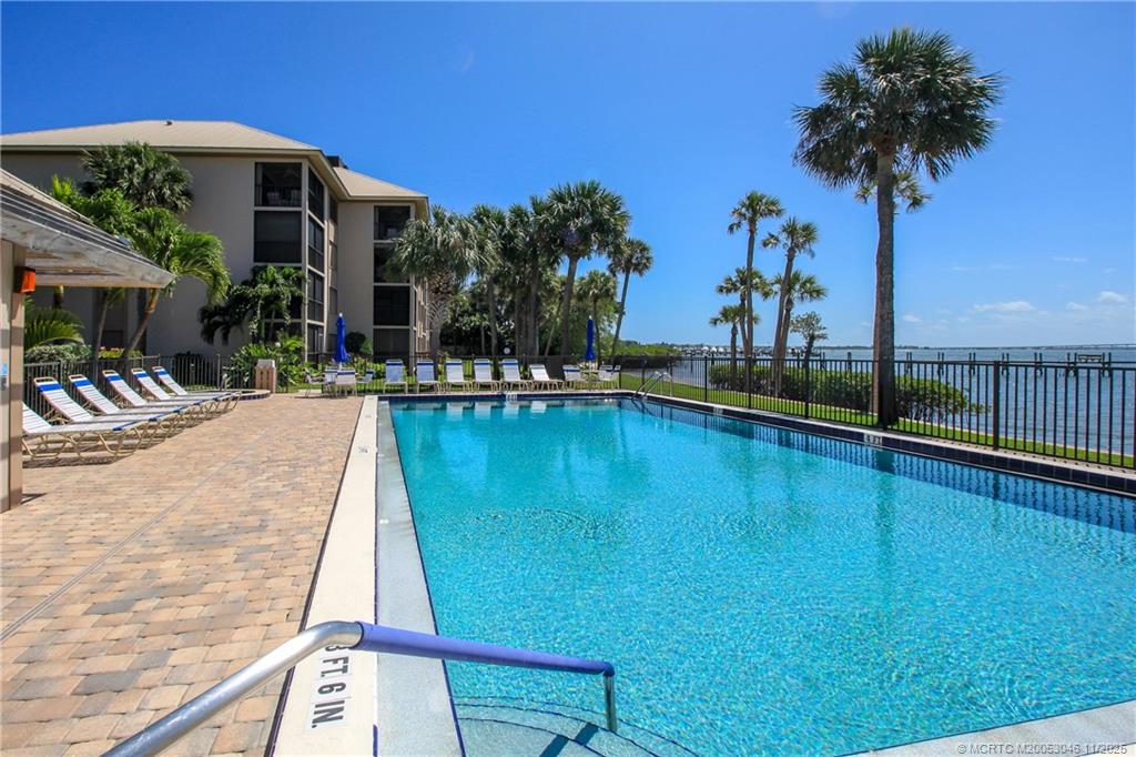 4720 Northeast Sandpebble Trace, Unit 403 Stuart, FL 34996 - Photo 36 of 40 a view of a swimming pool with a table and chairs