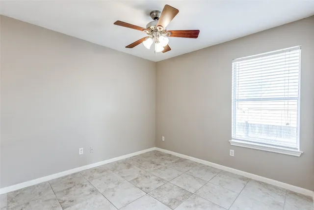an empty room with a window and a ceiling fan