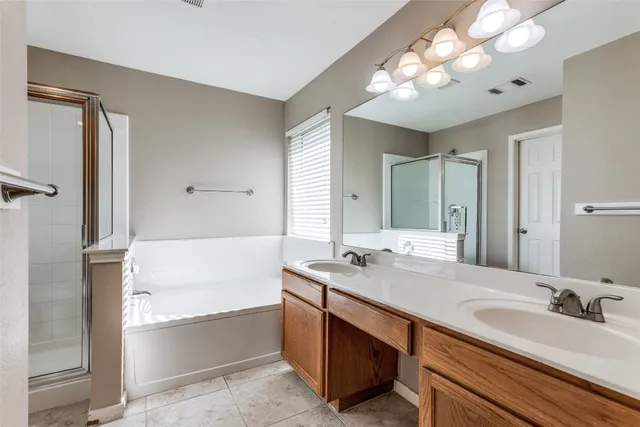 a large bathroom with a double vanity sink mirror and a bathtub with shower