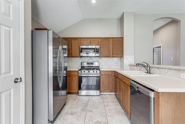a kitchen with stainless steel appliances granite countertop a sink stove and refrigerator