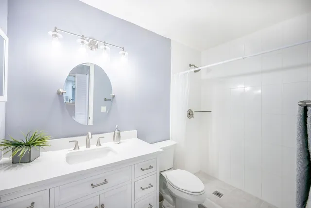 a bathroom with a toilet a sink a mirror a shower and vanity