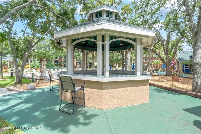 a view of patio with table and chairs with plants and trees