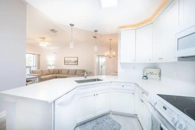 a kitchen with a sink a stove a refrigerator and white cabinets