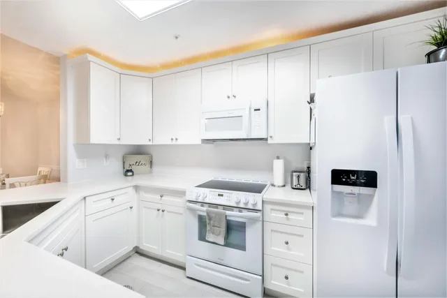 a kitchen with white cabinets and white appliances