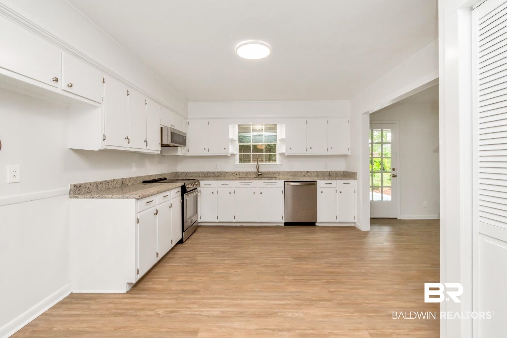 5217 Perin Road Mobile, AL 36693 - Photo 17 of 45 Spacious kitchen featuring white cabinetry, granite-finish countertops, stainless steel appliances, wood-finish flooring, and a glass-paned exterior door