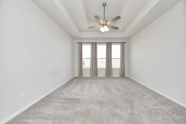 an empty room with a chandelier fan and windows