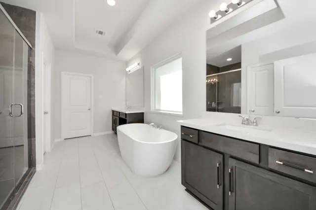 a spacious bathroom with a double vanity sink a mirror and a bathtub
