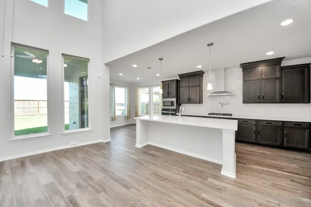 a large white kitchen with kitchen island a sink dishwasher a stove and a refrigerator with wooden floor