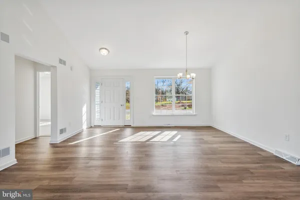 a view of an empty room with window and wooden floor