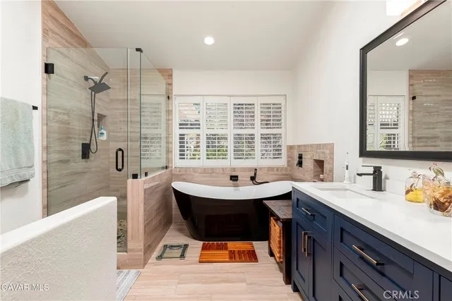 a spacious bathroom with a bathtub double sink and mirror