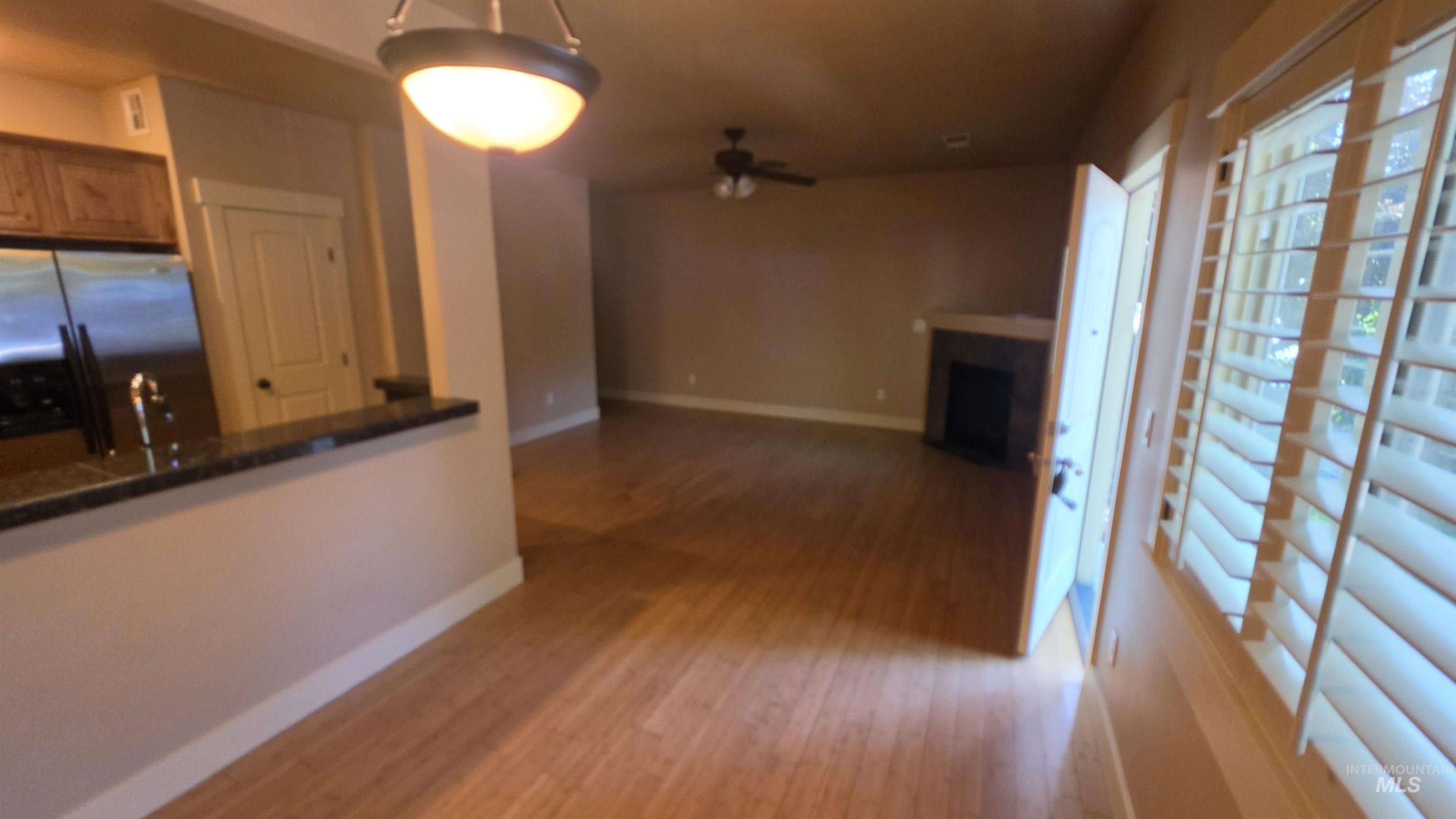 5239 West Morris Hill Road Boise, ID 83706 - Photo 2 of 19 Open concept living space featuring wood-finish flooring, a breakfast bar with stone countertop, stainless steel refrigerator, and a corner fireplace