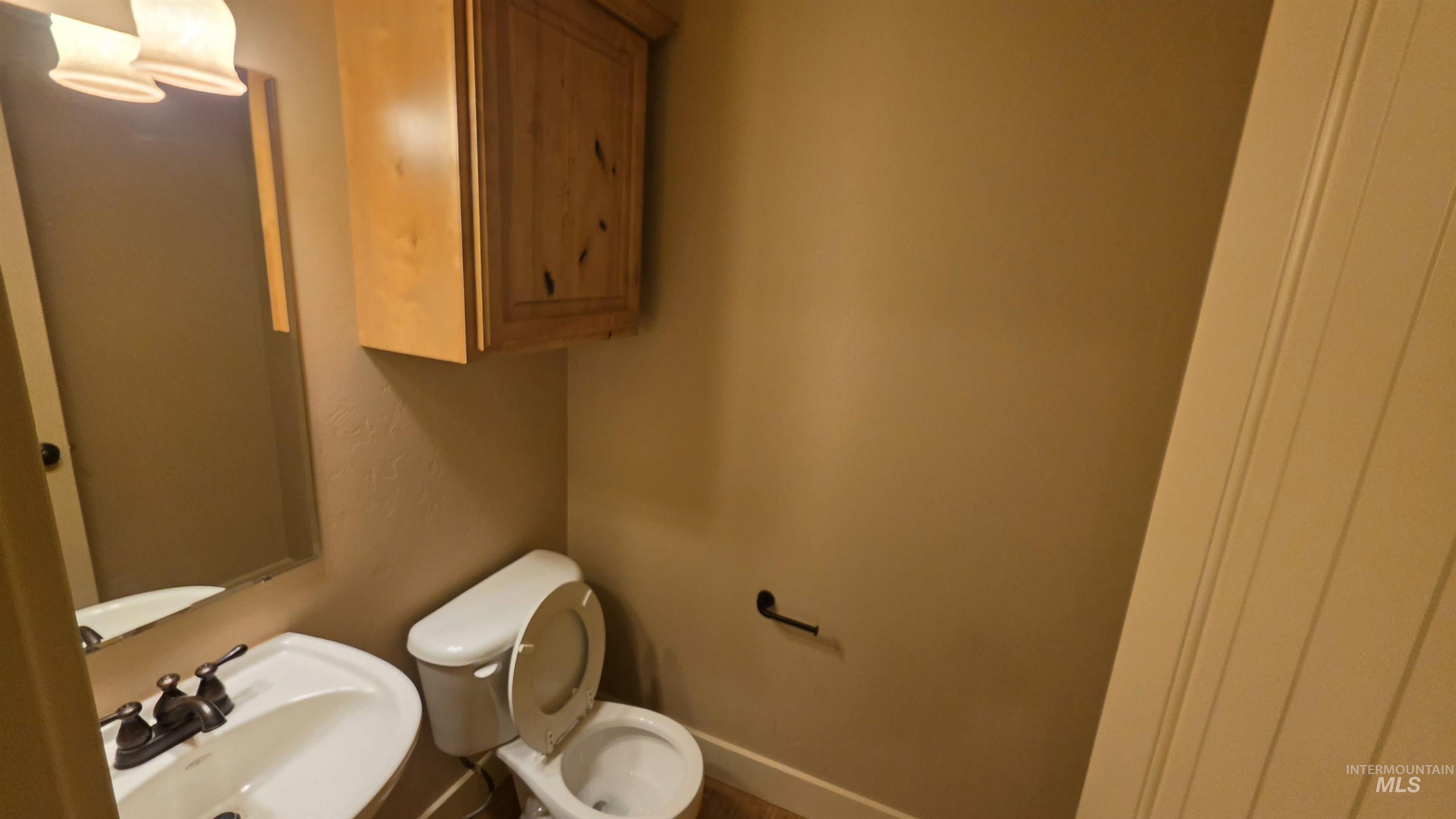 5239 West Morris Hill Road Boise, ID 83706 - Photo 6 of 19 Compact bathroom featuring a pedestal sink with a dual-handle faucet, a wall-mounted mirror, and overhead vanity lighting