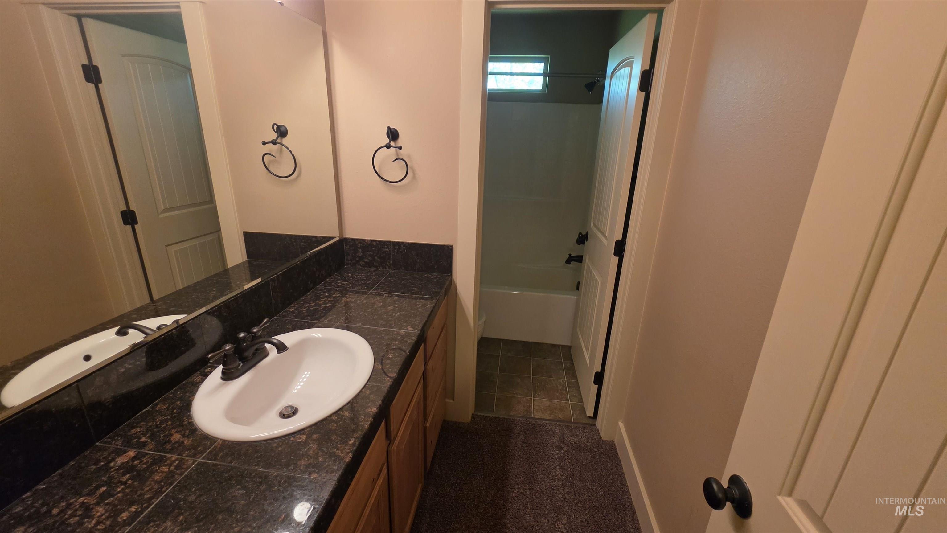 5239 West Morris Hill Road Boise, ID 83706 - Photo 10 of 19 Bathroom vanity featuring a single basin sink, dark stone countertop, and light wood cabinetry
