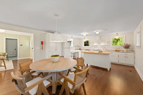 a kitchen with a dining table chairs and white cabinets
