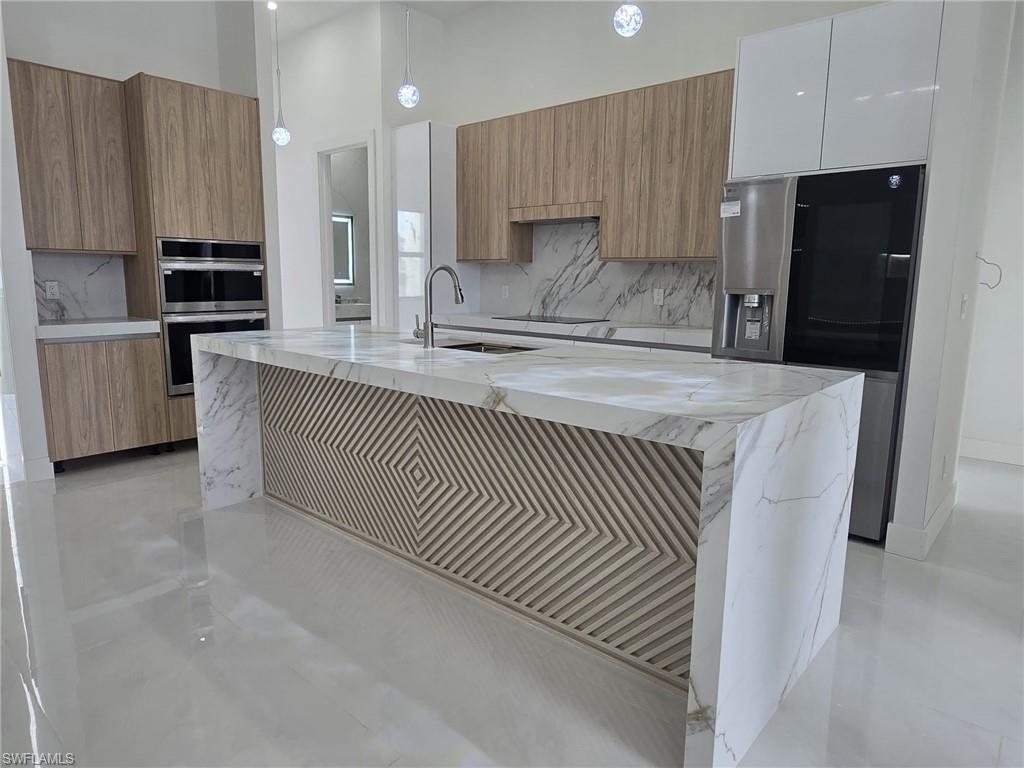 2006 Nelson Road North Cape Coral, FL 33993 - Photo 19 of 50 a kitchen with kitchen island granite countertop a sink a refrigerator and a stove