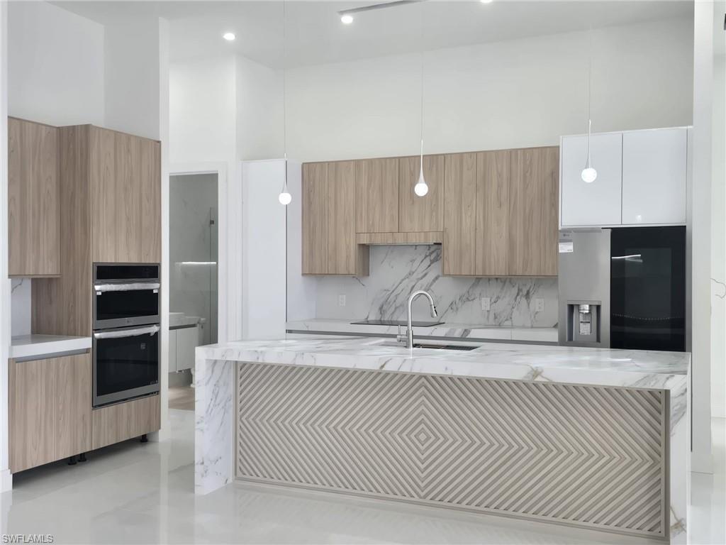 2006 Nelson Road North Cape Coral, FL 33993 - Photo 22 of 50 a kitchen with stainless steel appliances kitchen island granite countertop a refrigerator and a sink