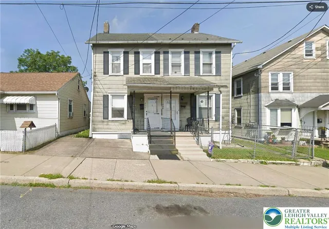 a view of a white house with large windows next to a road