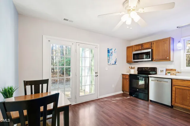 a kitchen with stainless steel appliances granite countertop a stove top oven a sink dishwasher a dining table and chairs with wooden floor