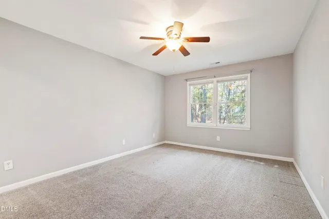 an empty room with ceiling fan and windows
