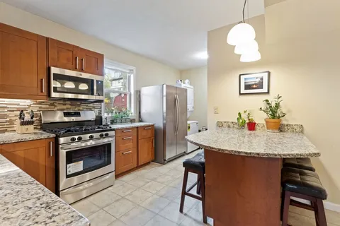 a kitchen with stainless steel appliances granite countertop a stove refrigerator a microwave oven with a dining table and chairs