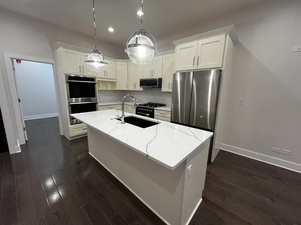 a kitchen with a refrigerator a microwave oven on a table and chairs