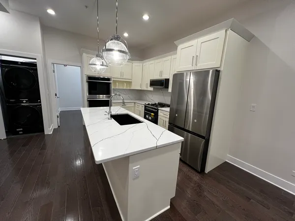 a kitchen with sink a refrigerator and wooden floor