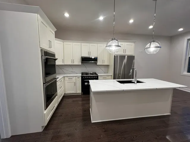 a kitchen with a refrigerator a microwave oven on a table and chairs