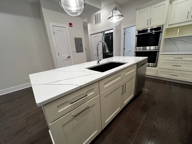 a kitchen with granite countertop white cabinets and stainless steel appliances