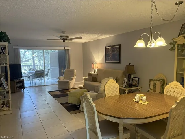 a living room with couches a fireplace and a dining table with wooden floor