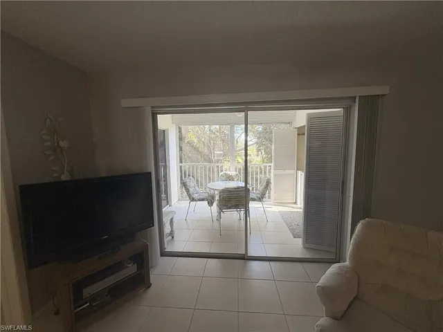 a living room with furniture a flat screen tv and a floor to ceiling window