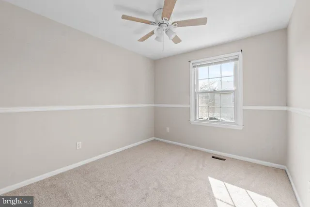 an empty room with a window and a fan