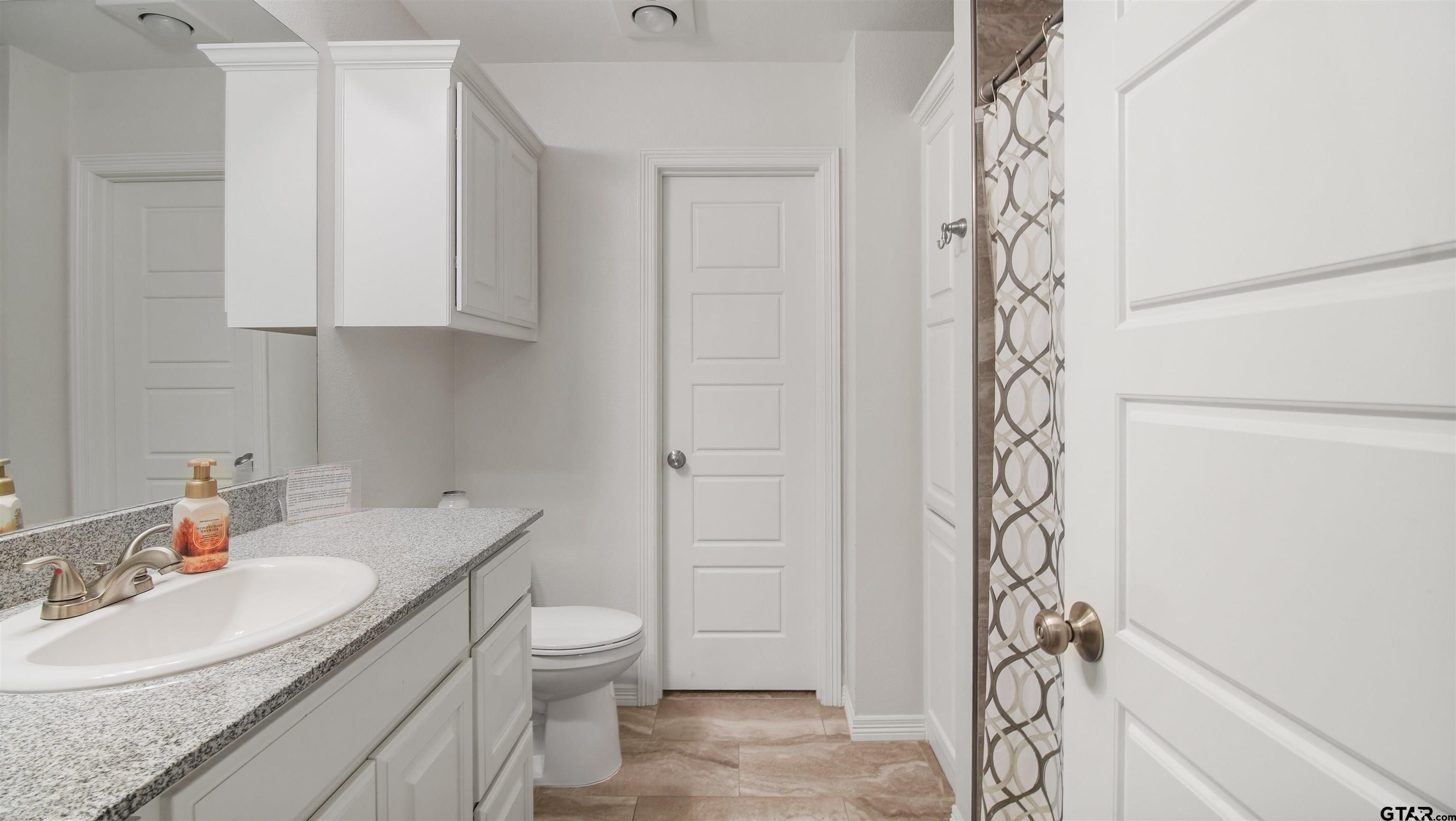 2220 Walton Road Tyler, TX 75701 - Photo 17 of 29 a bathroom with a granite countertop sink a toilet and shower