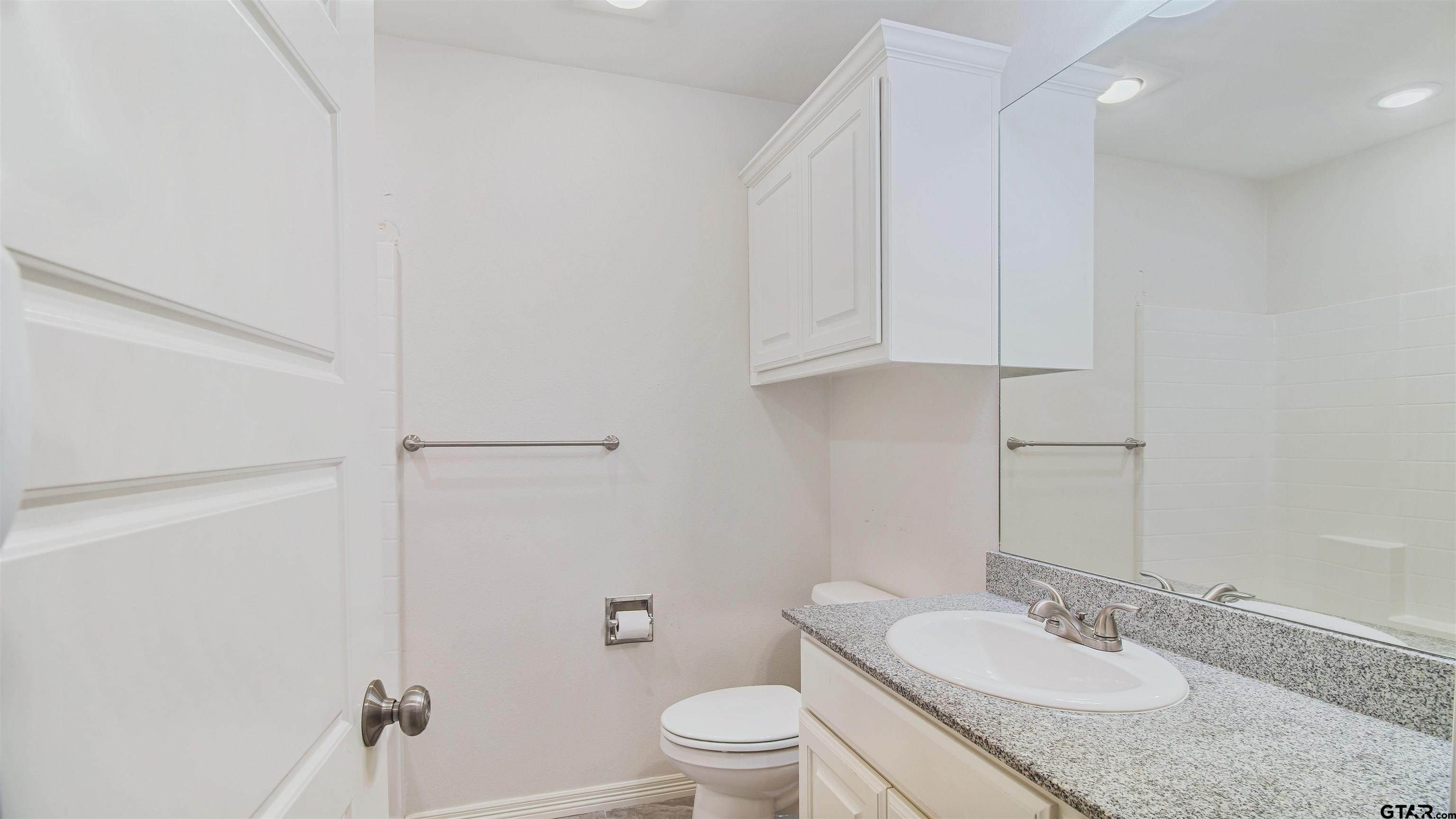 2220 Walton Road Tyler, TX 75701 - Photo 24 of 29 a bathroom with a granite countertop sink a toilet and a mirror