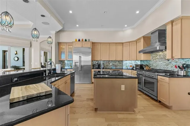 a kitchen with stainless steel appliances granite countertop a sink a stove and a wooden floors
