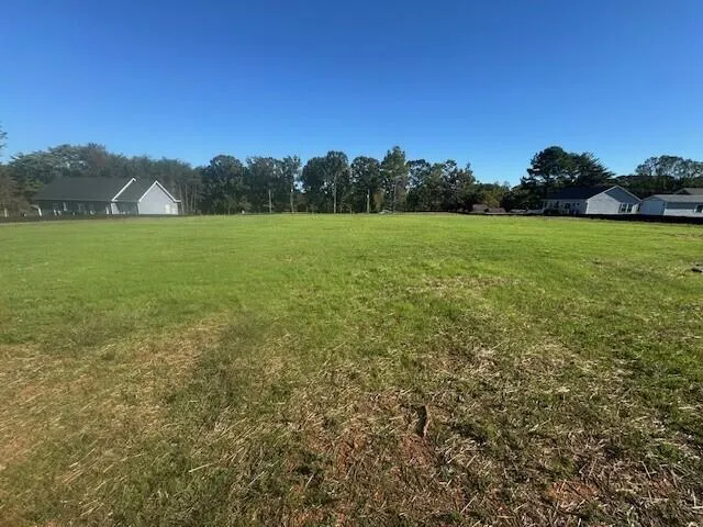 a view of a green field with wooden fence