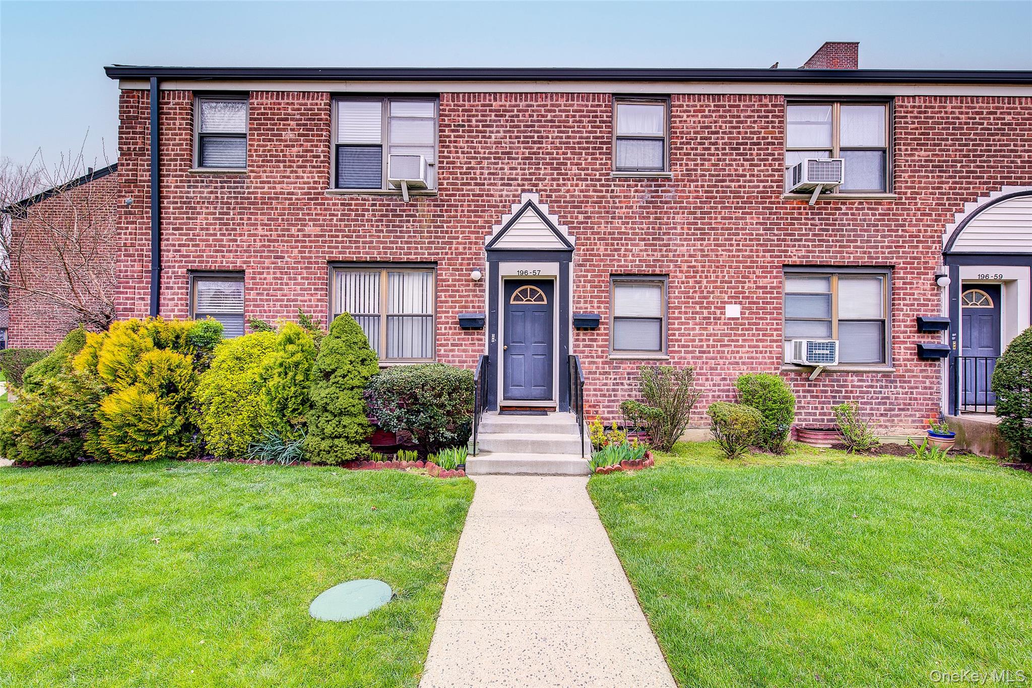 196-57 69th Avenue, Unit 1 Queens, NY 11365 - Photo 2 of 18 front view of a brick house with a yard
