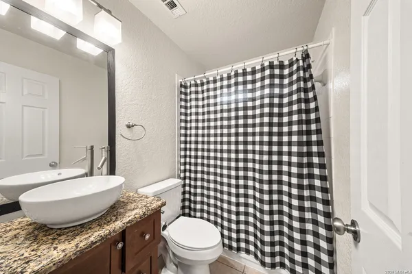 a bathroom with a granite countertop toilet a sink and a mirror