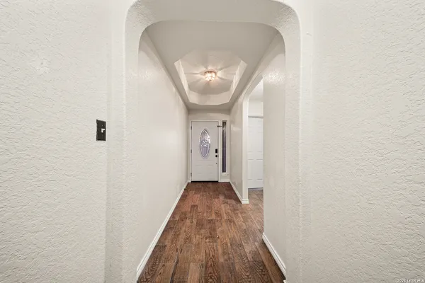 a view of a hallway with wooden floor and a chandelier