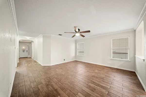 a view of empty room with wooden floor and fan