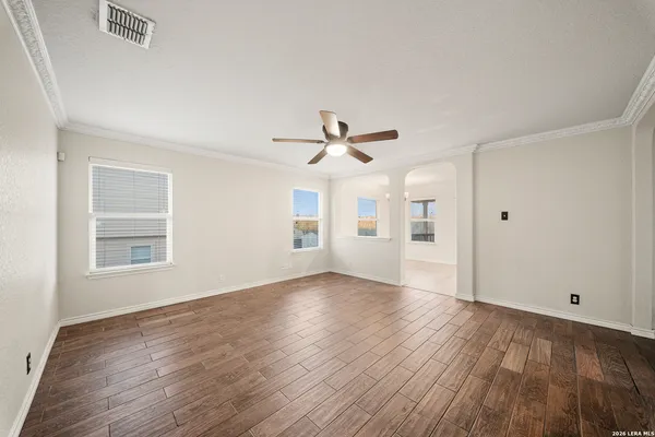 a view of empty room with wooden floor and ceiling fan
