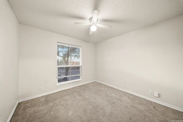 an empty room with windows and fan