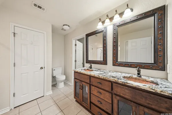 a bathroom with a granite countertop double vanity sink and a mirror
