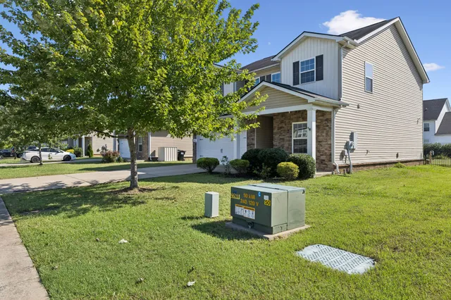 a view of a house with a yard and large tree