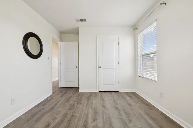 a view of an empty room with wooden floor and a window