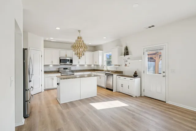 a kitchen with granite countertop a sink stainless steel appliances and white cabinets
