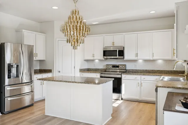 a kitchen with stainless steel appliances granite countertop a refrigerator a stove and a sink